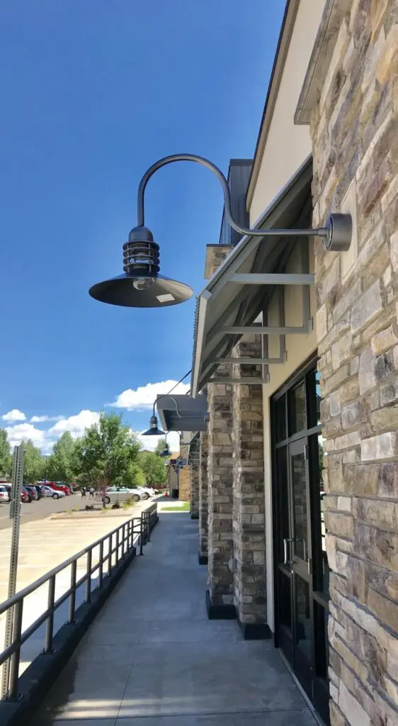Outdoor vintage-style lamps on a stone building facade under a clear blue sky.