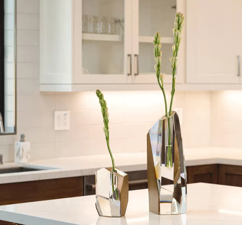Modern kitchen with sleek metallic vases on a white countertop.