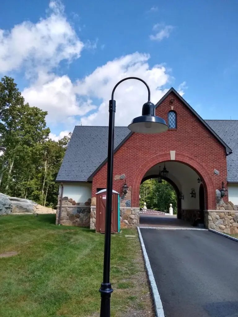 Historic red brick gatehouse with arched entrance under a blue sky.