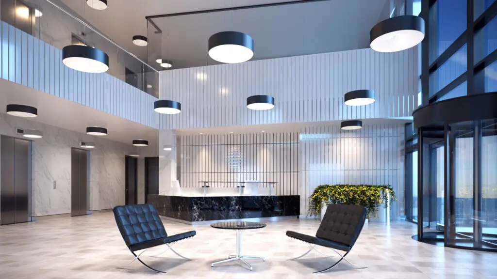 Modern lounge area with black chairs and round tables under ceiling lights.