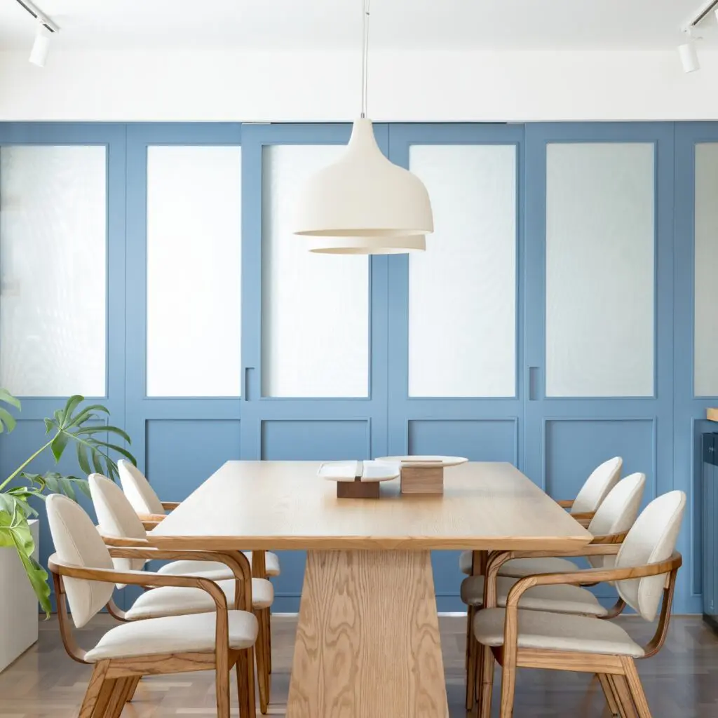 Modern dining room with wooden table and white chairs under pendant light.