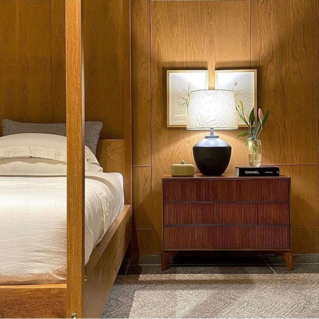 Cozy bedroom corner with wooden bed frame and modern nightstand lamp.