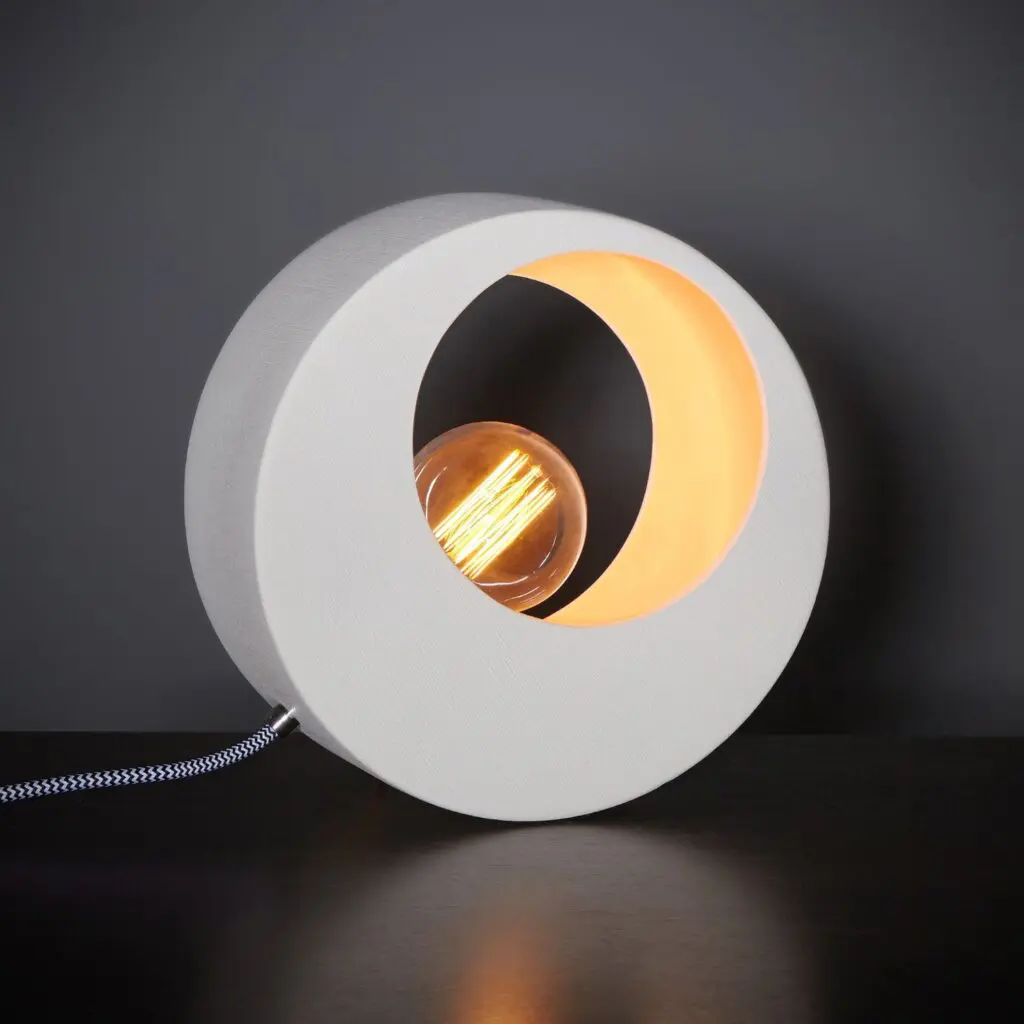 Modern circular lamp with a warm glowing bulb inside.